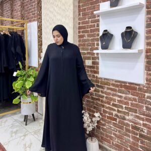Woman in black abaya, jewelry display.