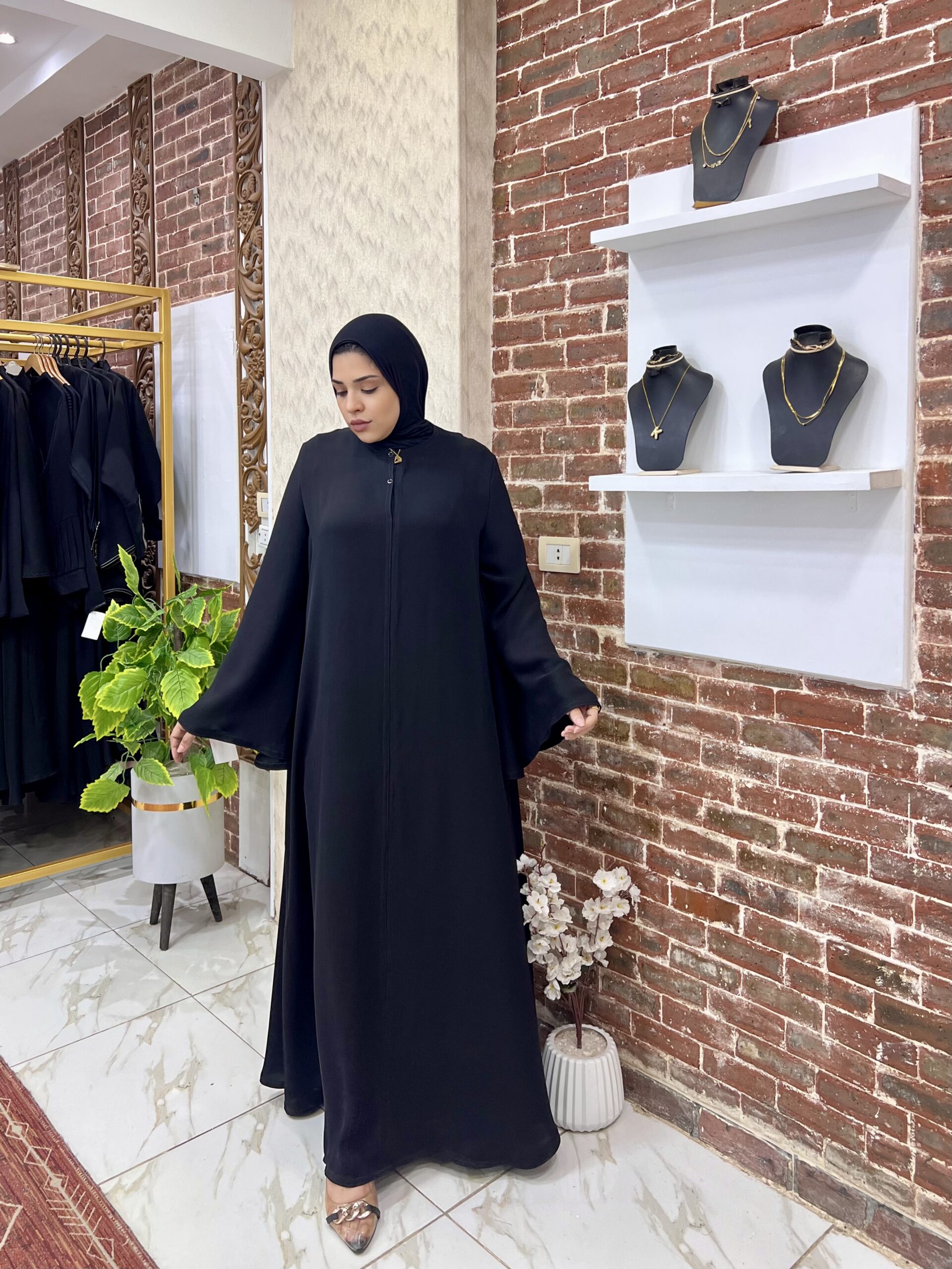 Woman in black abaya, jewelry display.